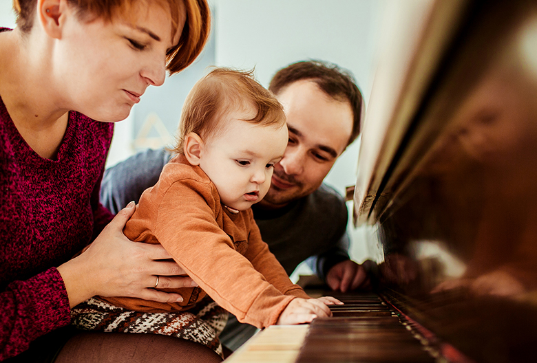 Little girl looks funny playing with mother on the piano